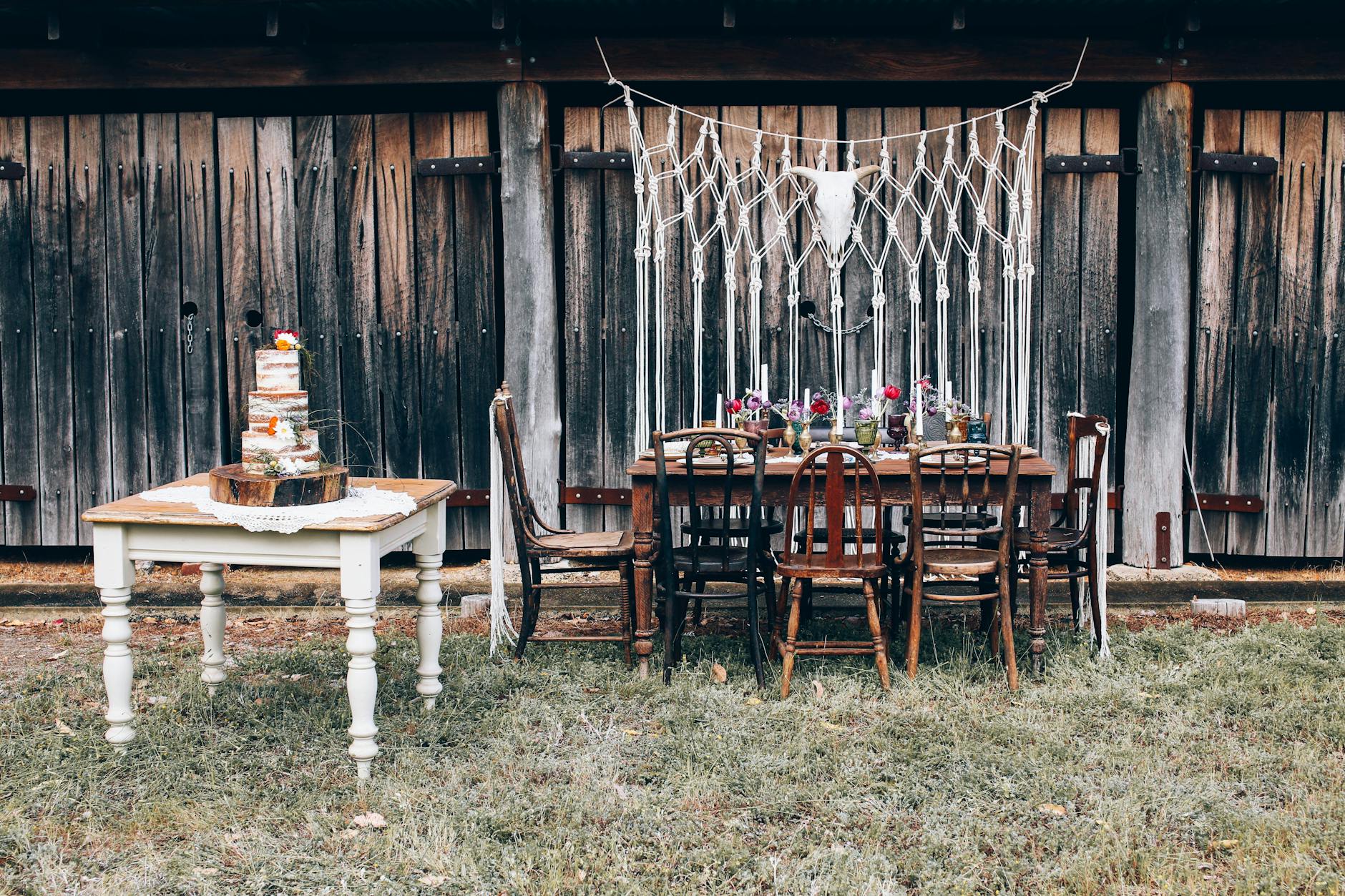 Rustyczna aranżacja stołu weselnego na zewnątrz z nagim tortem i kwiatami