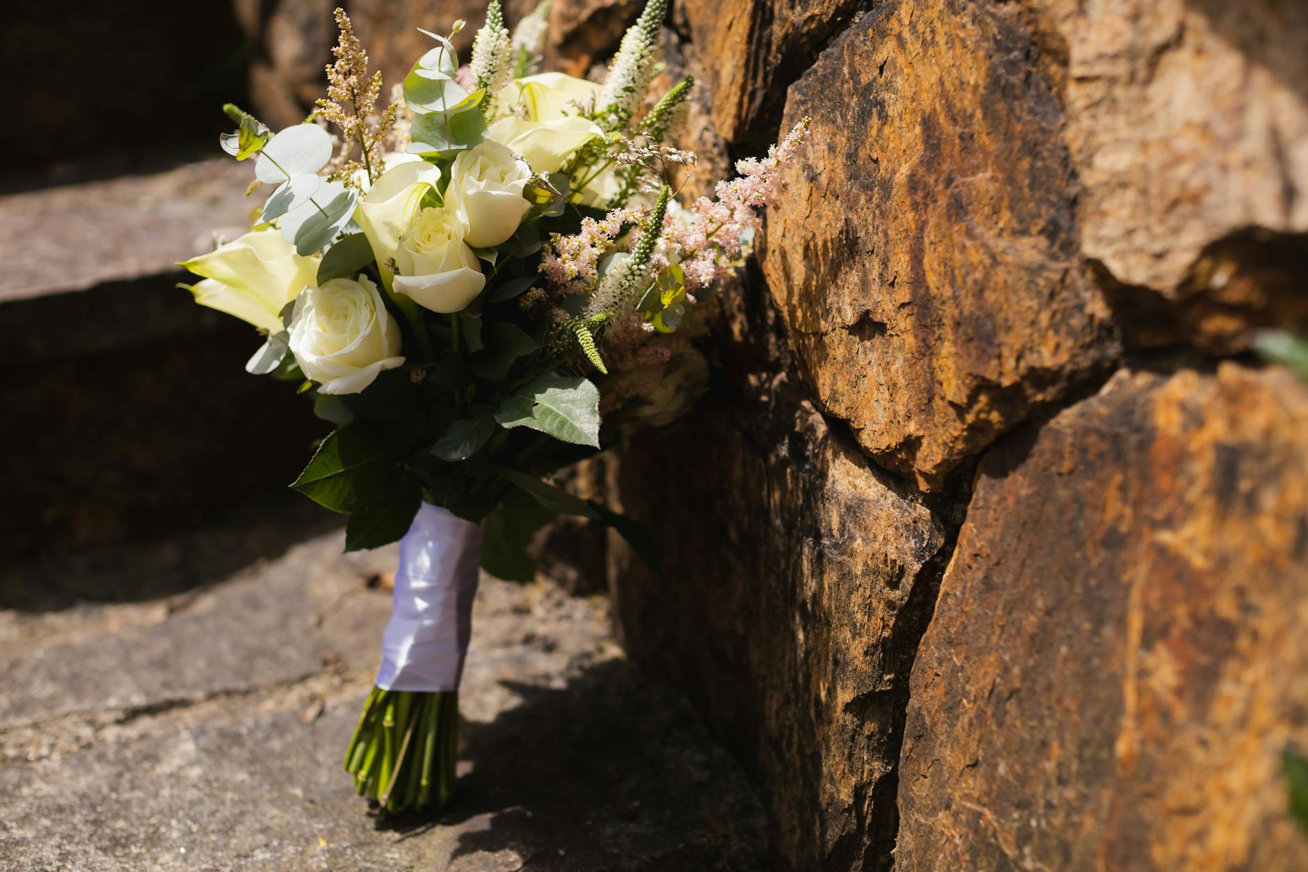 Delikatny bukiet ślubny w stylu vintage oparty o kamienny mur