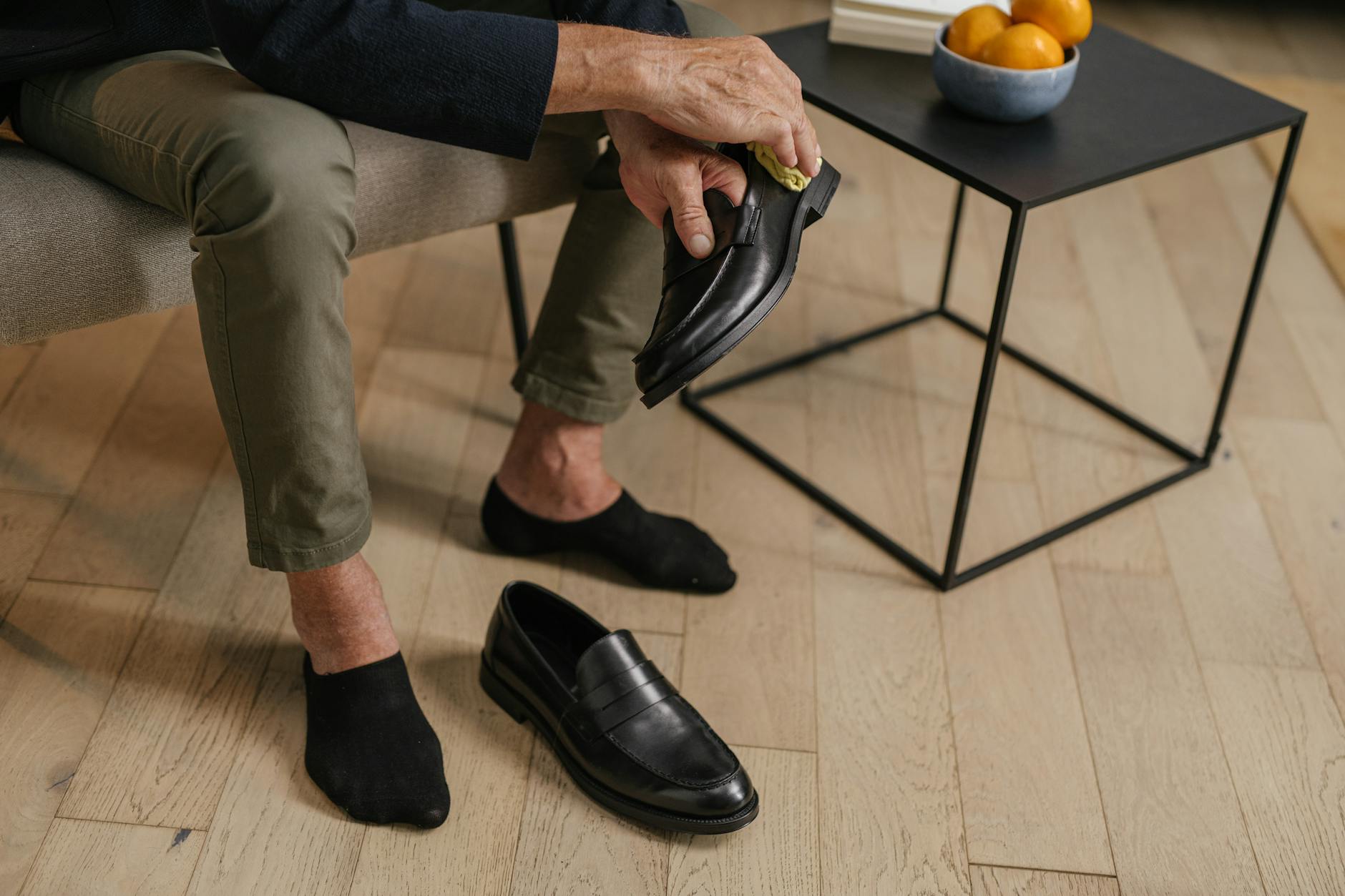 Starszy mężczyzna poleruje czarne skórzane buty w domu