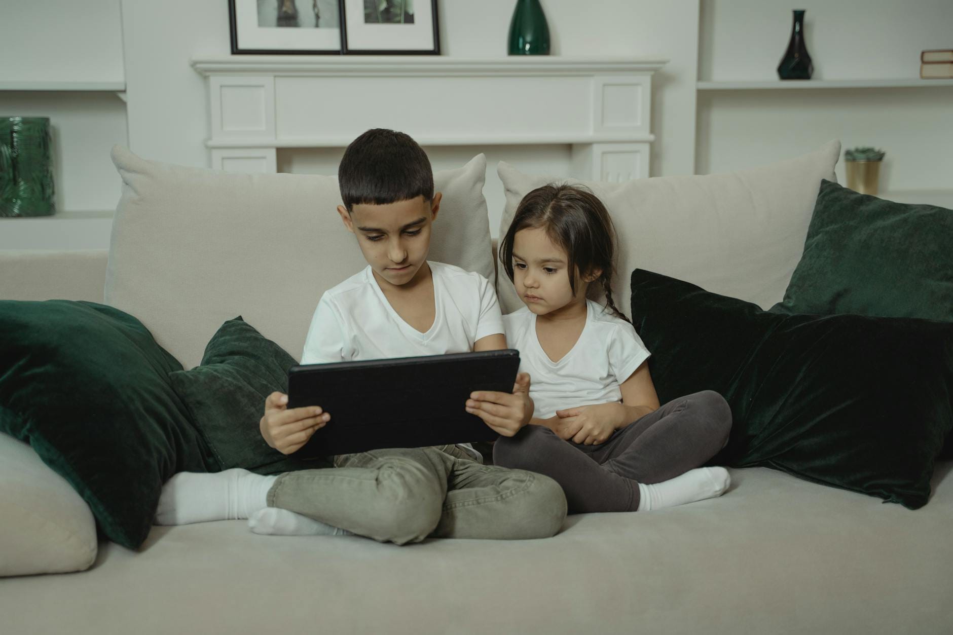 Chłopiec i dziewczynka na sofie korzystają razem z tabletu