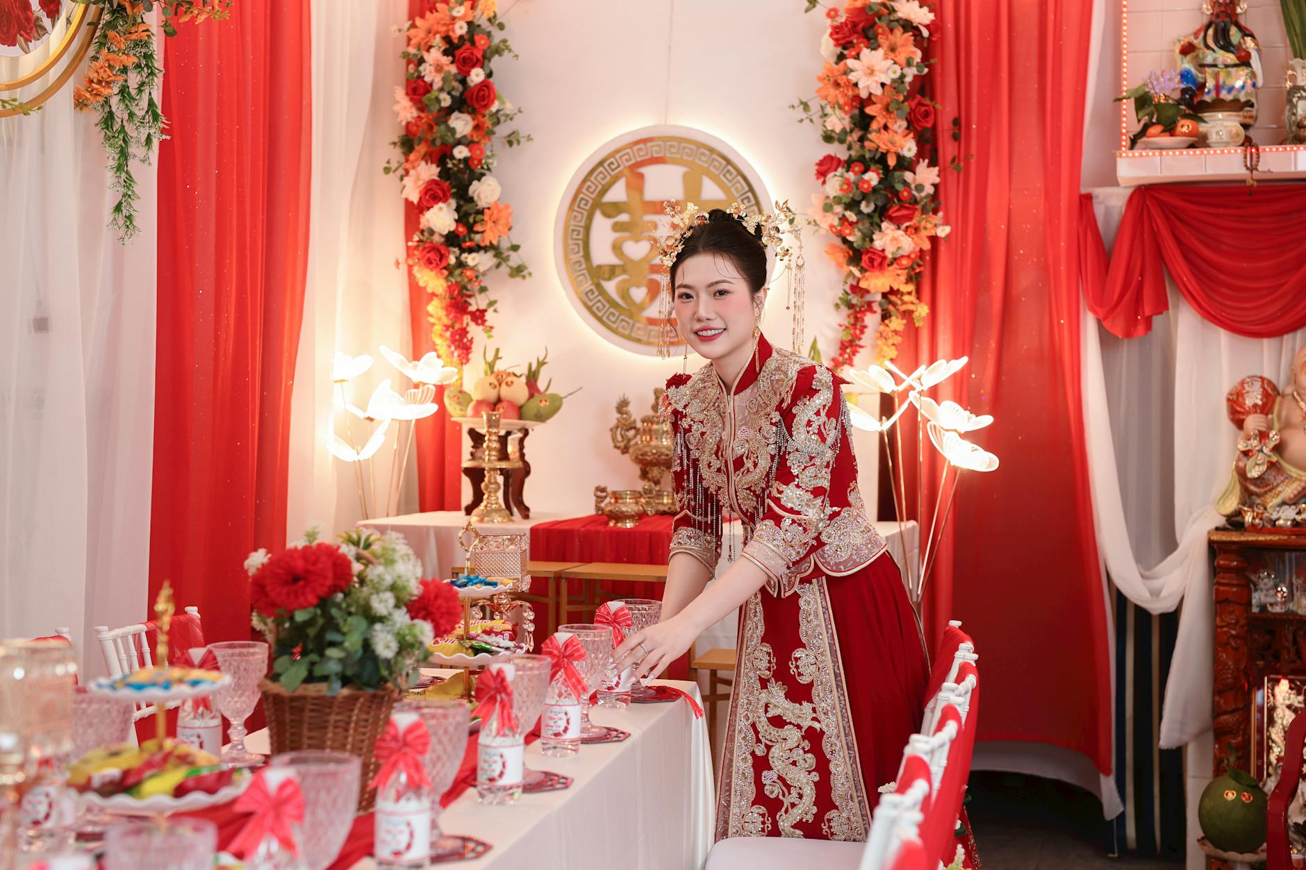 Kobieta w tradycyjnym stroju układa czerwone dekoracje na weselnym stole