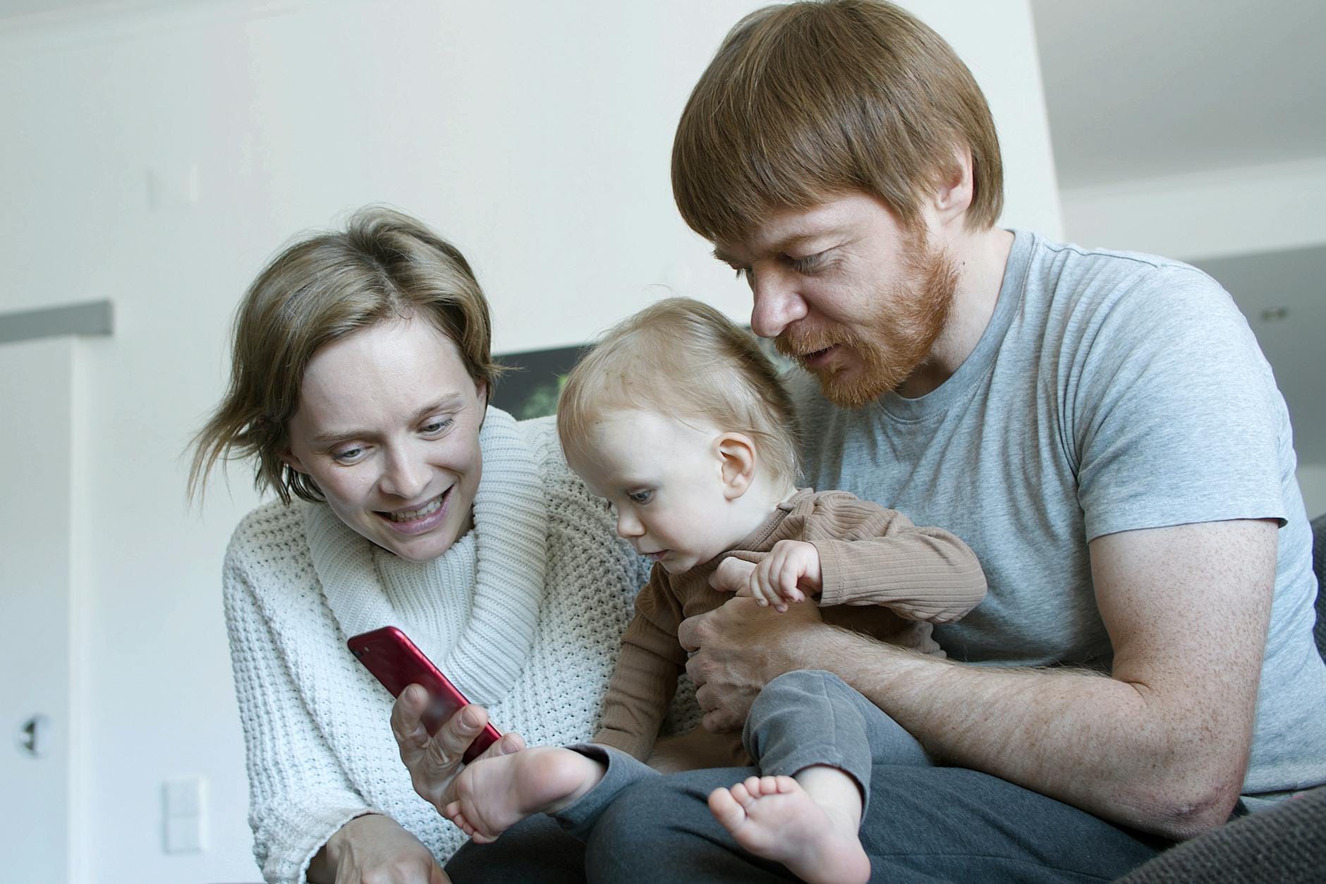 Rodzina na kanapie w salonie wspólnie korzysta ze smartfona