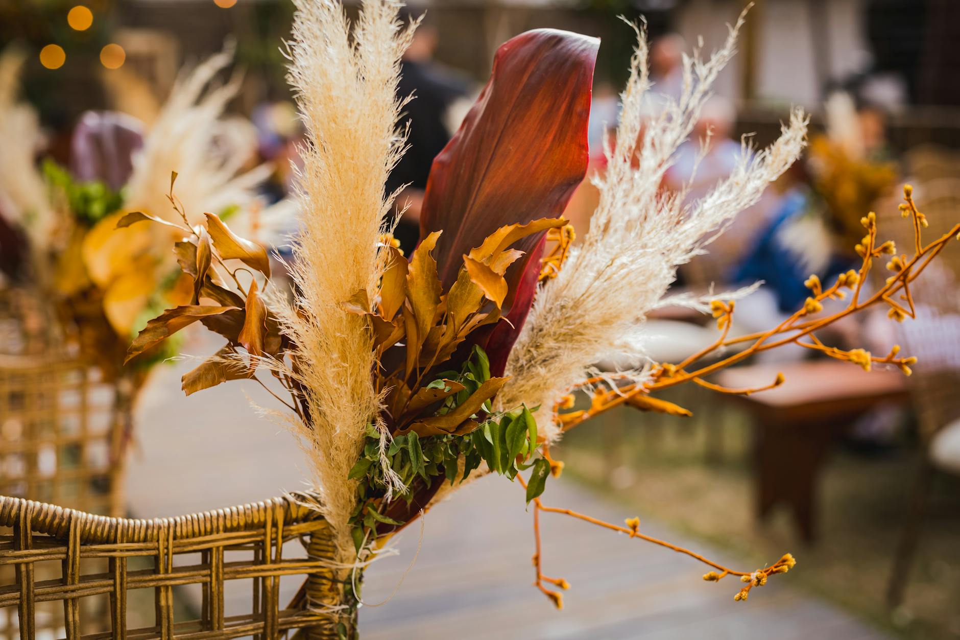 Suszona kompozycja kwiatowa w odcieniach ziemi na wiklinowym krześle na zewnątrz